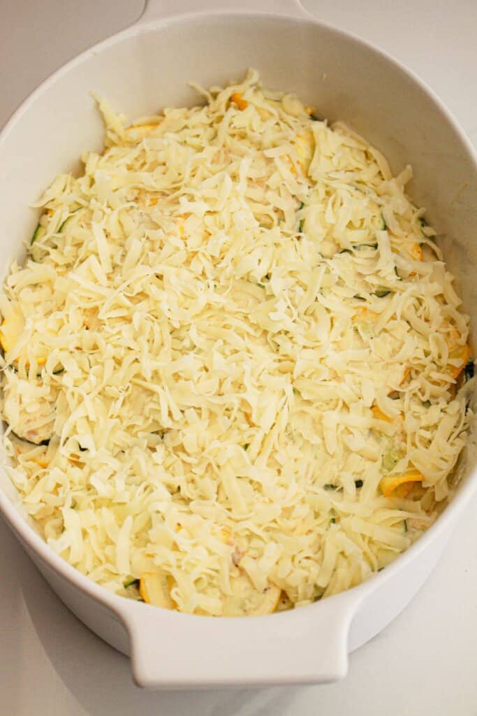 shredded mozzarella cheese being sprinkled on top of a casserole dish.
