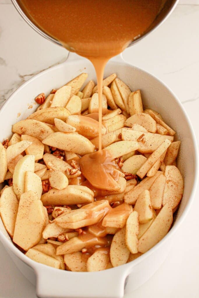 Caramel sauce being poured over apple slices.