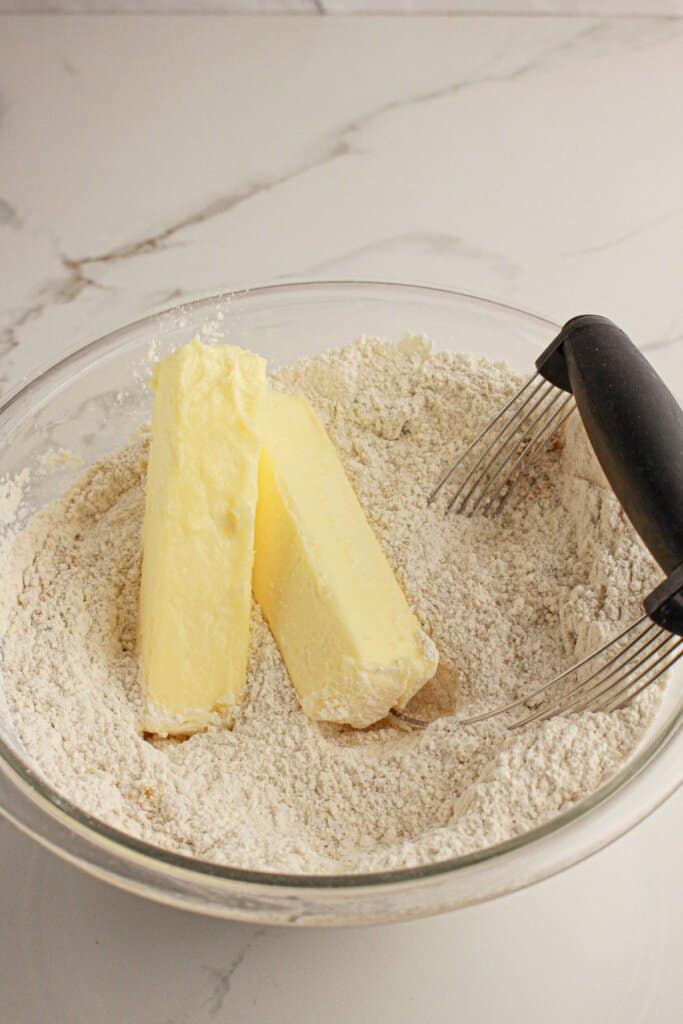 Butter being cut into flour in a glass mixing bowl.