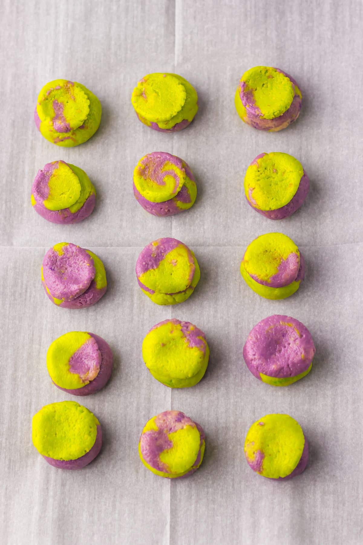 Crushed cookies dyed green and purple and shaped into circles on a baking sheet.