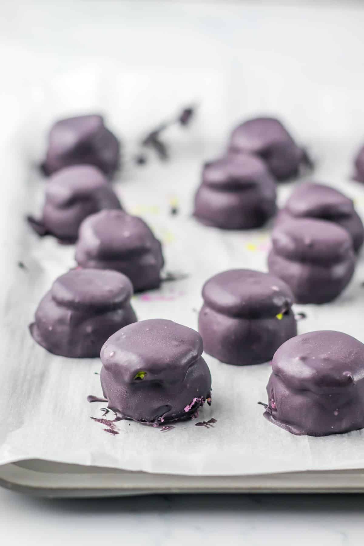 Oreo truffles being dippedi nto black melted candy wafers/