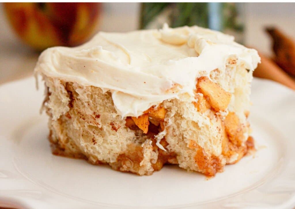 Peach cobbler cinnamon roll on a small plate on a table.