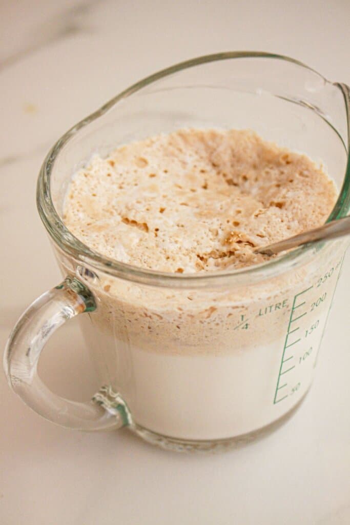Yeast and warm milk being bloomed in a measuring cup.