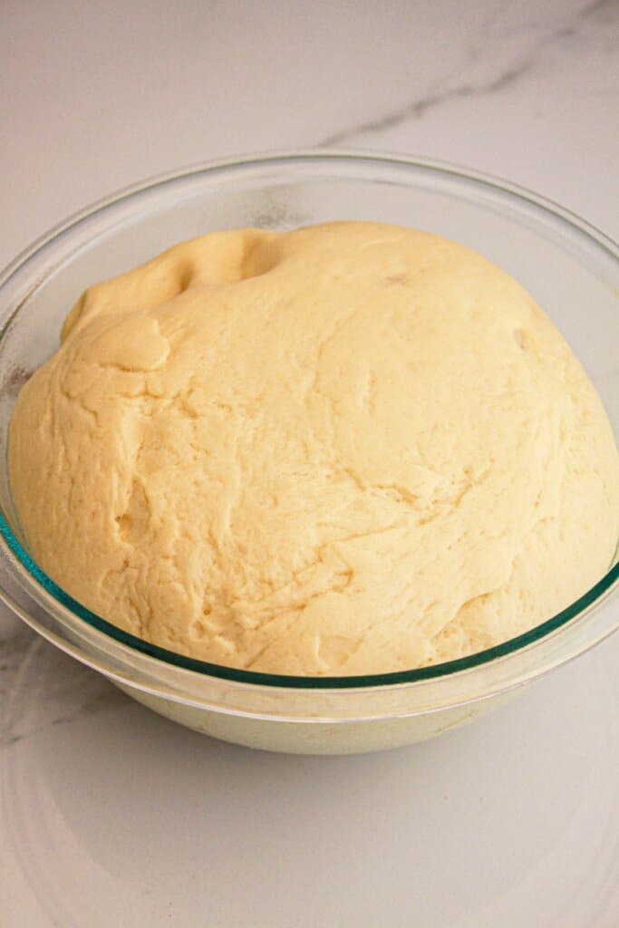 Dough rising in a glass mixing bowl.