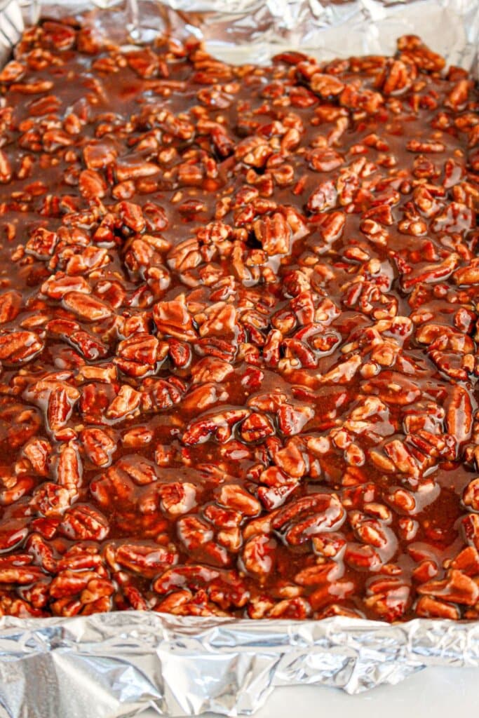 caramel pecan mixture being poured onto crackers.