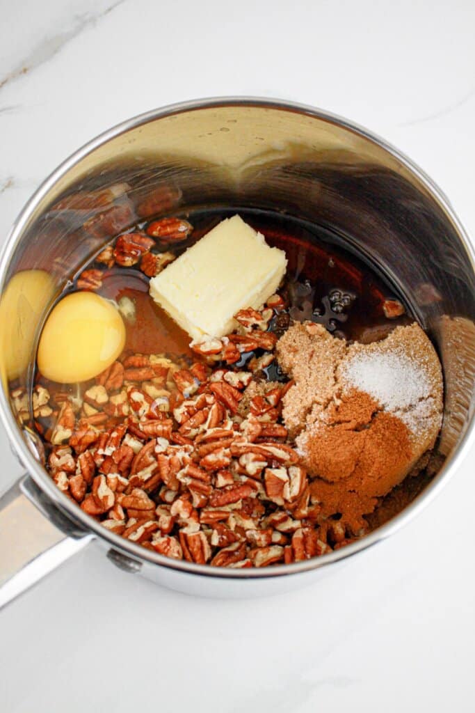 Pecans, egg, butter, cinnamon, and brown sugar in a saucepan.