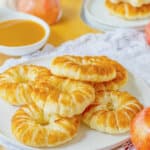 Six puff pastry apple doughnuts on a plate.