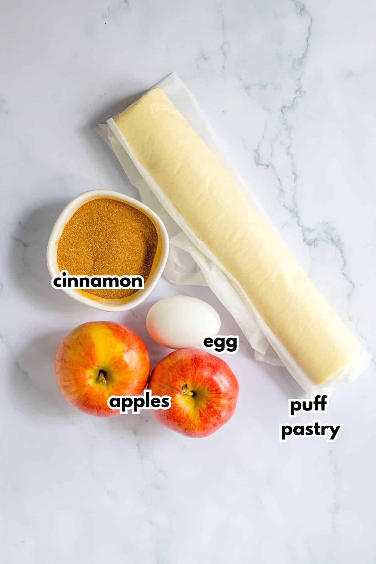 puff pastry, cinnamon, apples, and egg on a counter.