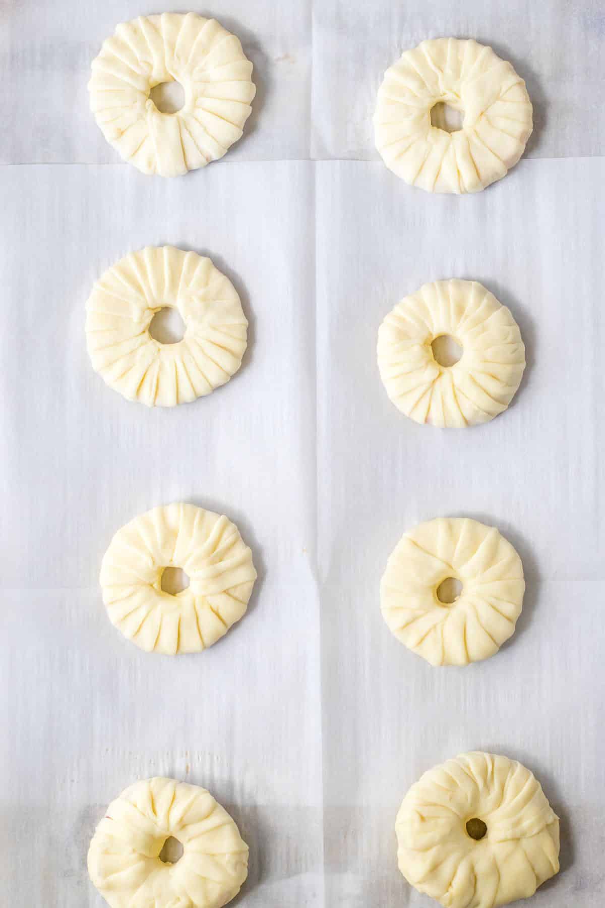 Puff pastry being wrapped around an apple slice.