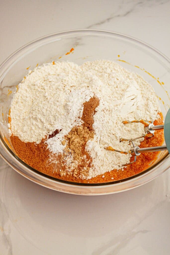 Dry ingredients being mixed into the wet ingredients with a hand mixer.