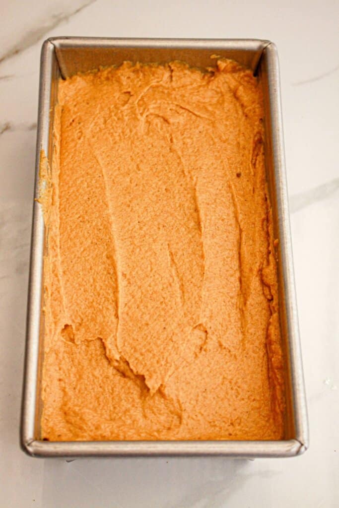 Pumpkin bread batter spread into a loaf pan and ready for the oven.