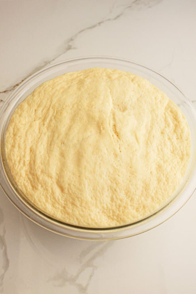 Dough rising in a glass mixing bowl.