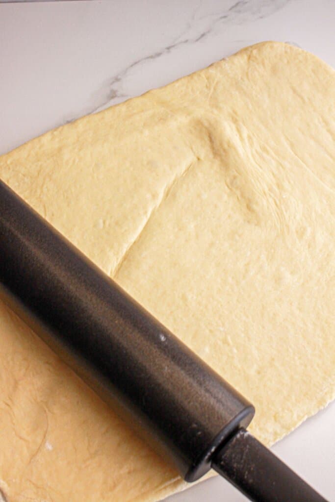 Dough being rolled out onto a flat surface.