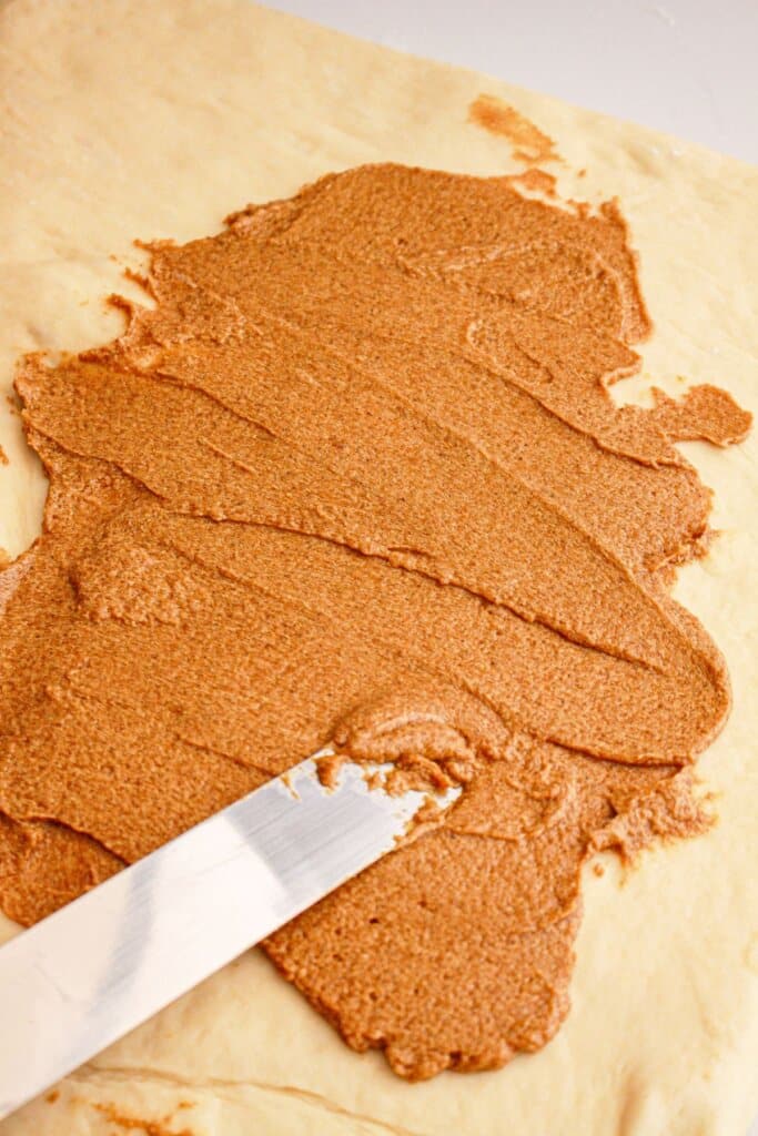 Pumpkin and cinnamon mixture being spread on top of dough.