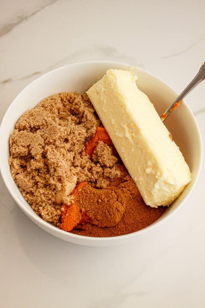 Butter, brown sugar, cinnamon and pumpkin puree being mixed in a small bowl.