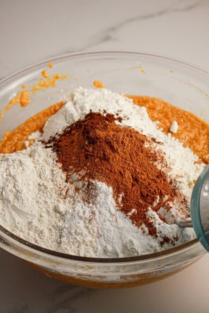 Dry ingrediens being added to wet ingredients in a glass mixing bowl.