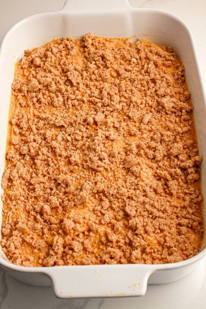 Stresuel topping being sprinkled on top of dessert in a baking dish.