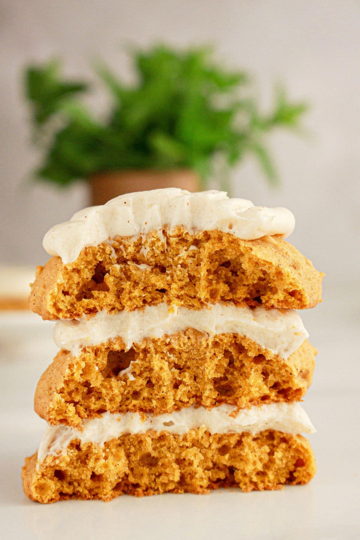 Three halves of pumpkin cookies stacked on top of each other on a table.