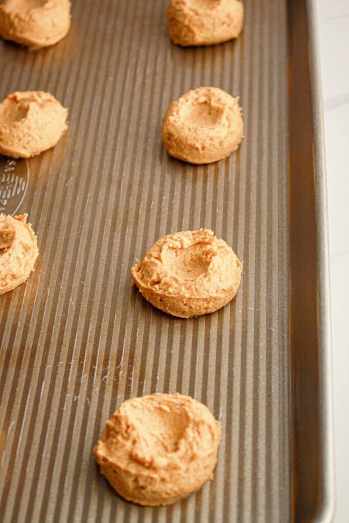 Cookie dough being pressed on a baking sheet.