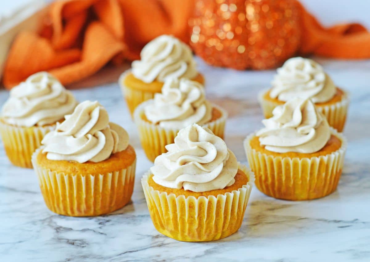 Seven pumpkin cupcakes on a counter.