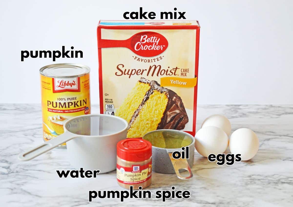 Can of pumpkin, box of cake mix, water, oil, pumpkin spice, and eggs on a counter.