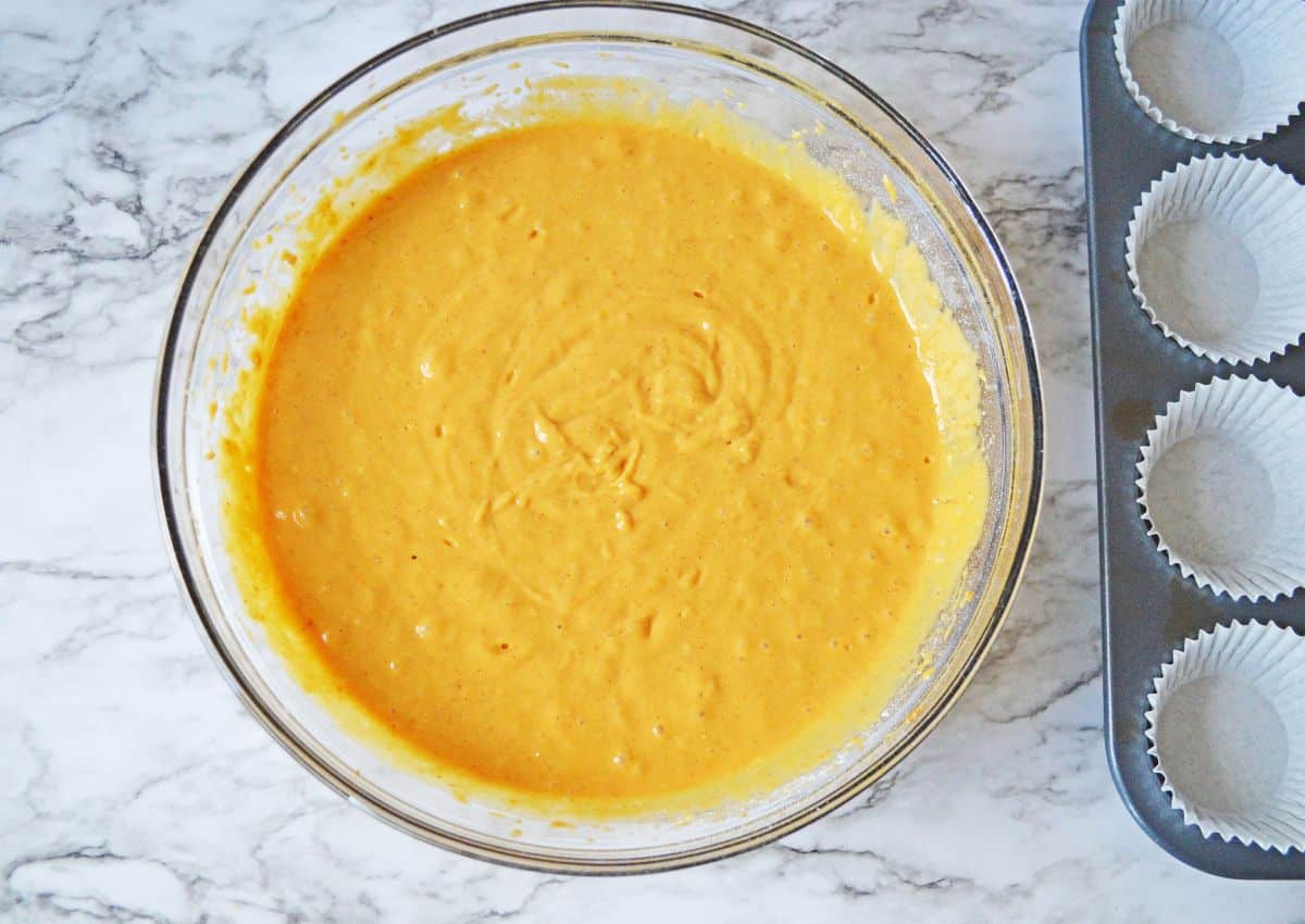 Cake batter being mixed in a large glass mixing bowl.
