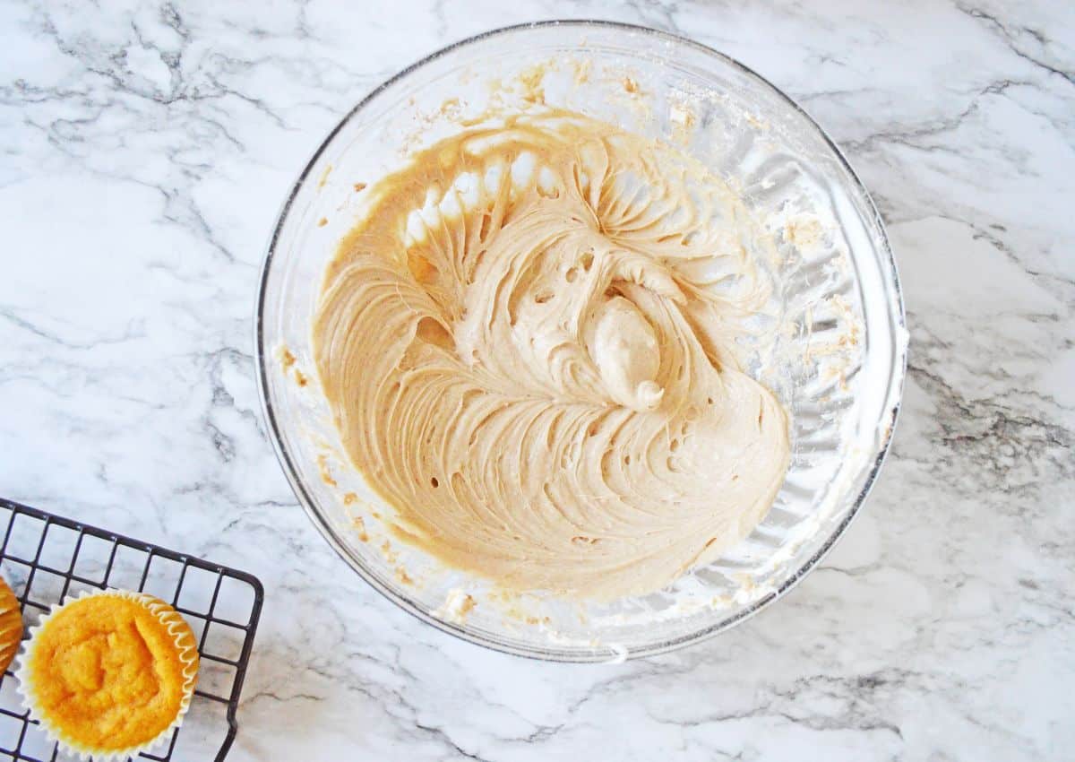 Cream cheese, sugar, and cinnamon being mixed in a large glass bowl.