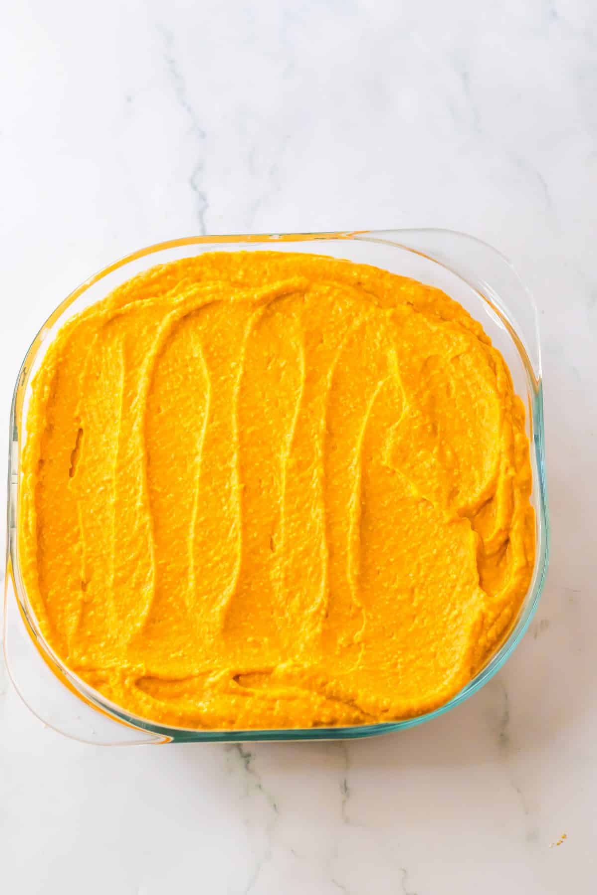 Pumpkin layer being spread on top of the dessert.