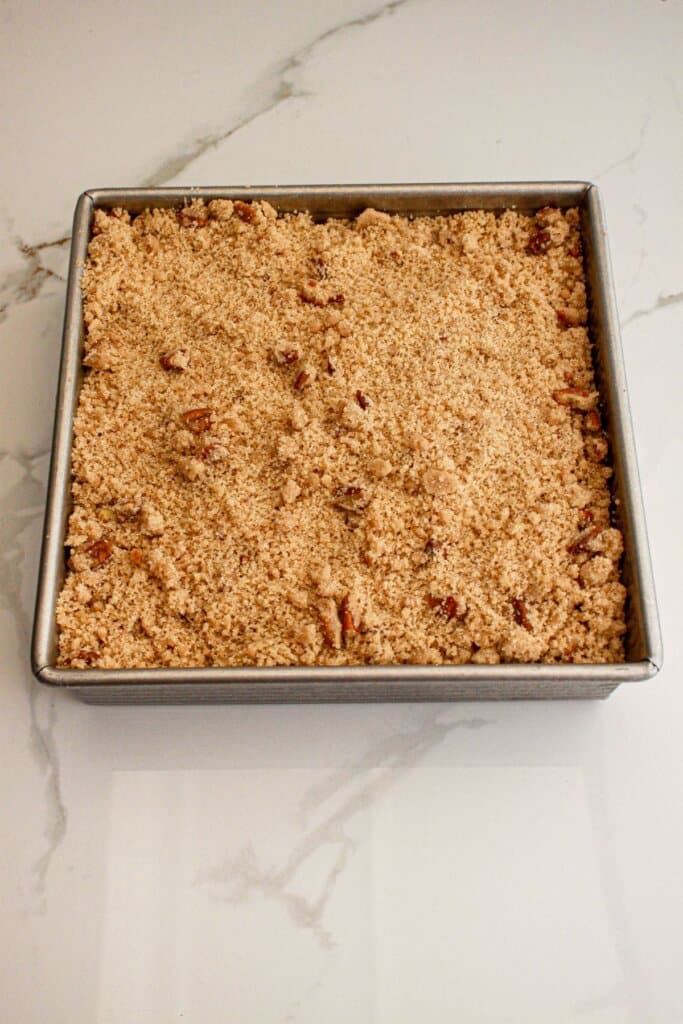 Streusel topping being sprinkled over the top of a baking dish.