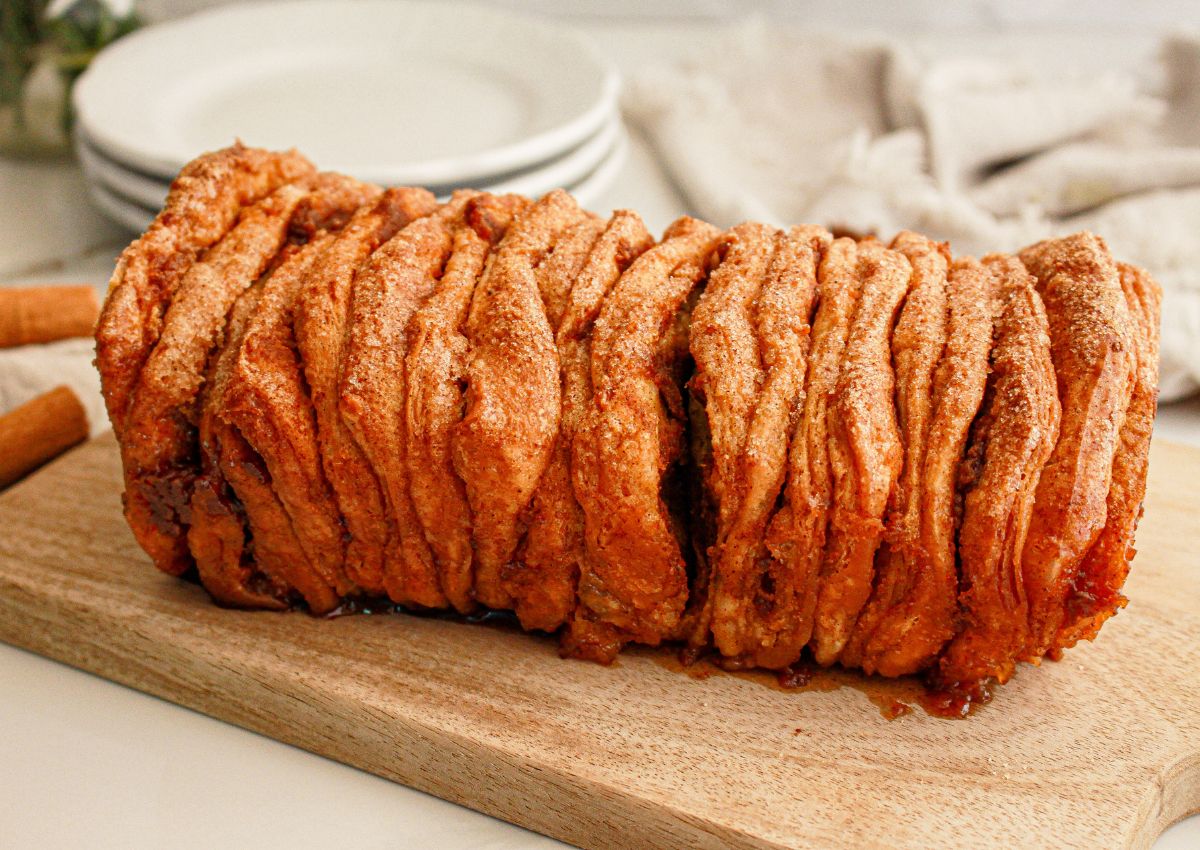 Whole loaf of pumpkin pull apart bread on a wooden cutting board.