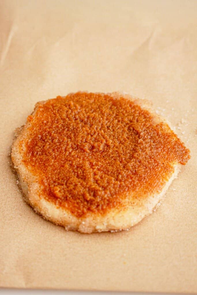 Pumpkin pie filling being spread on top of a piece of biscuit.