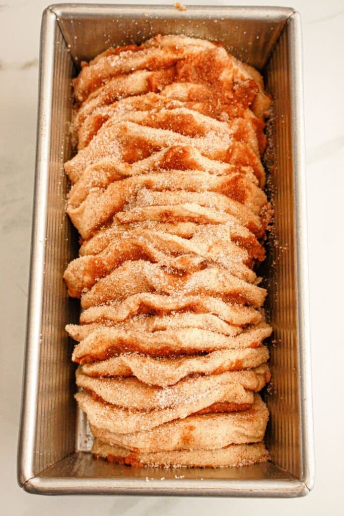 Biscuit slices coated in cinnamon sugar in a loaf pan.