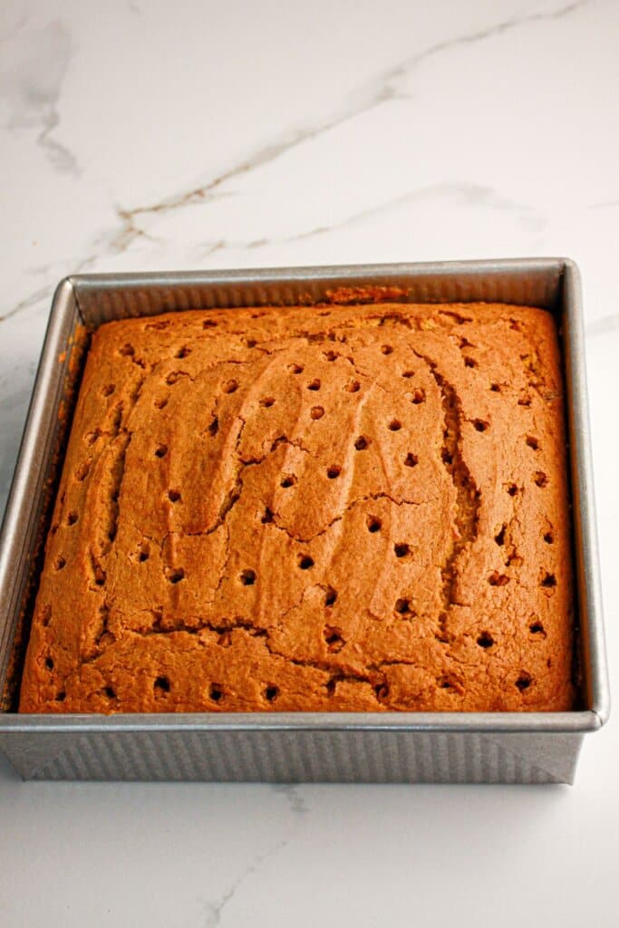 Holes being poked into a cake in a baking pan.