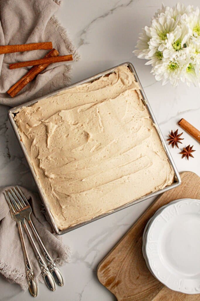 Frosting being spread on time of a cake in a baking pan.