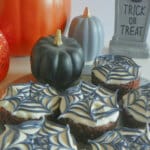 Six spider web brownie on a wooden cutting board.