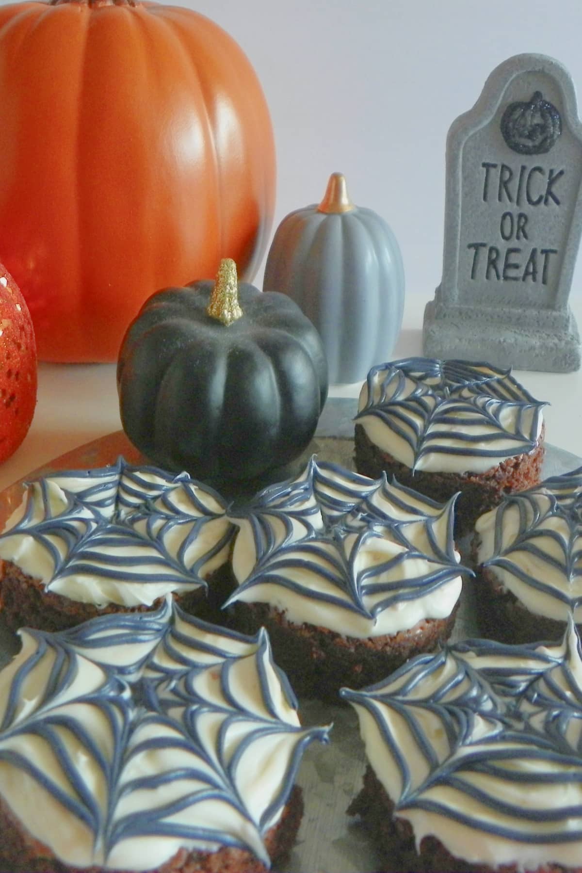 Six spider web brownie on a wooden cutting board.