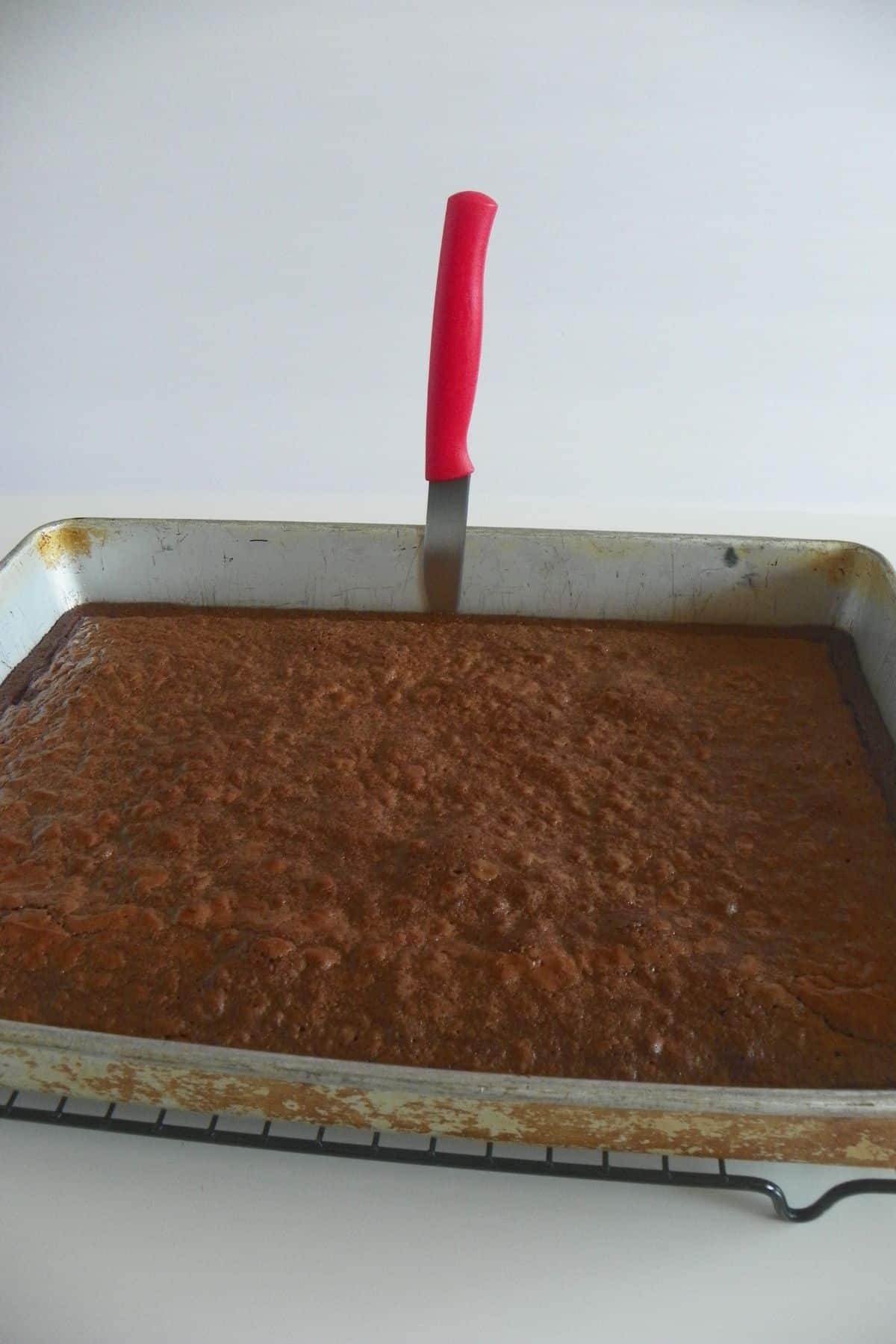 Knife being used to remove the sides of the brownies from the pan.