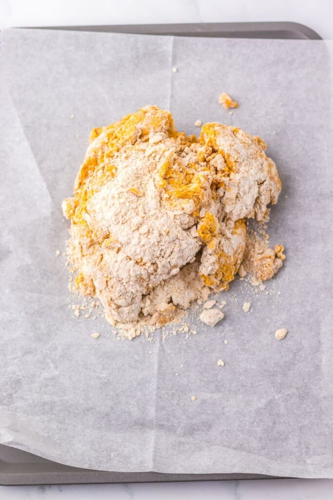 Dough being shaped on a parchment lined baking sheet.
