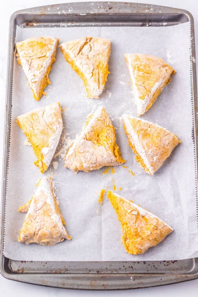 Scone dough cut into triangles on a parchment lined baking sheet.