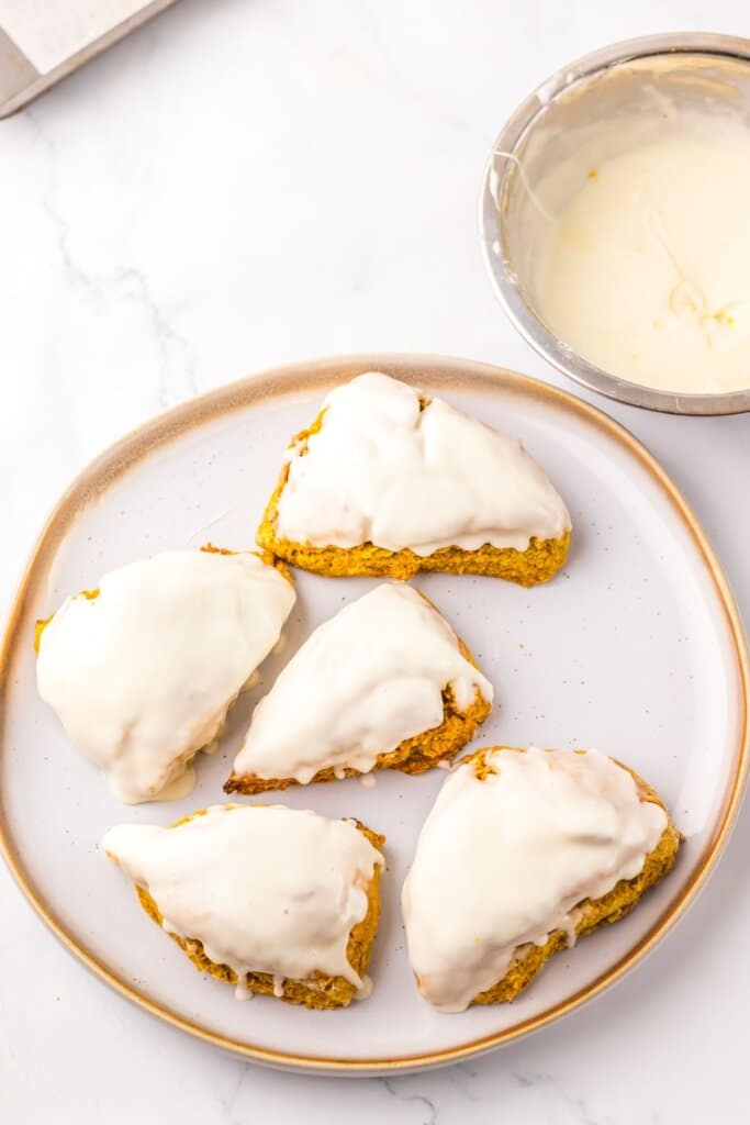 Scones dipped in glaze on a plate.