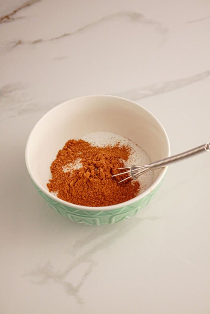 Cinnamon and sugar being mixed in a bowl.