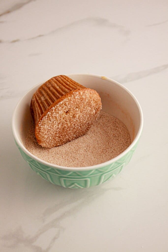 muffin being rolled in cinnamon sugar.