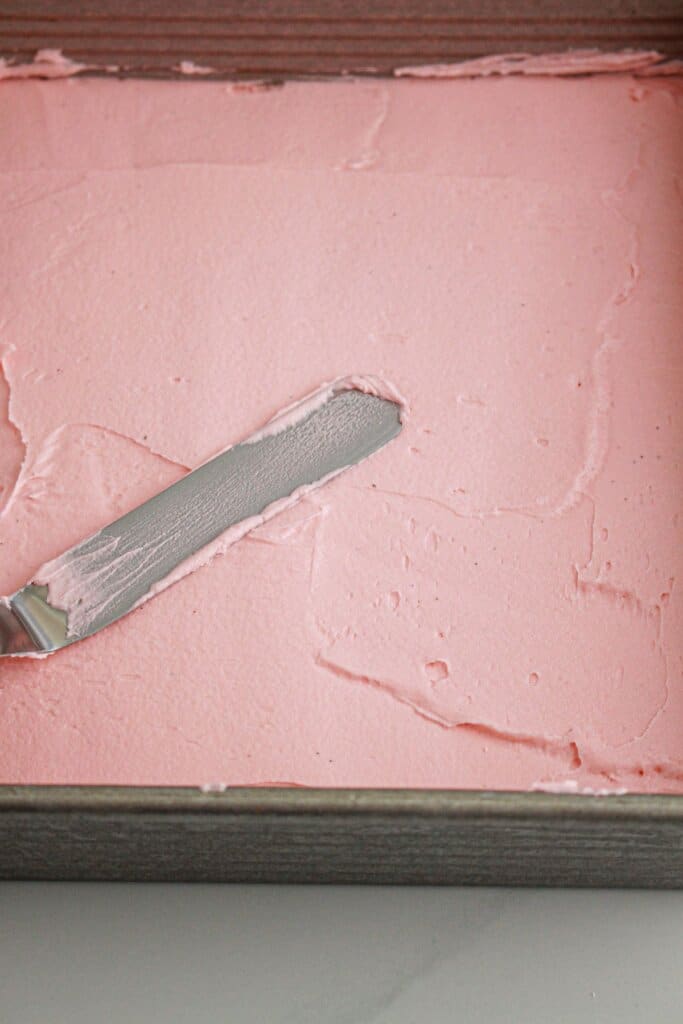 Frosting being spread on brownies.