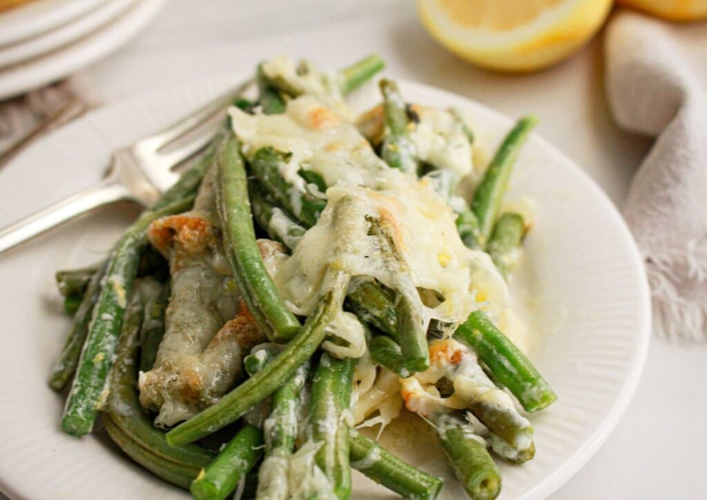 Green beans topped with mozzarella cheese on plate.