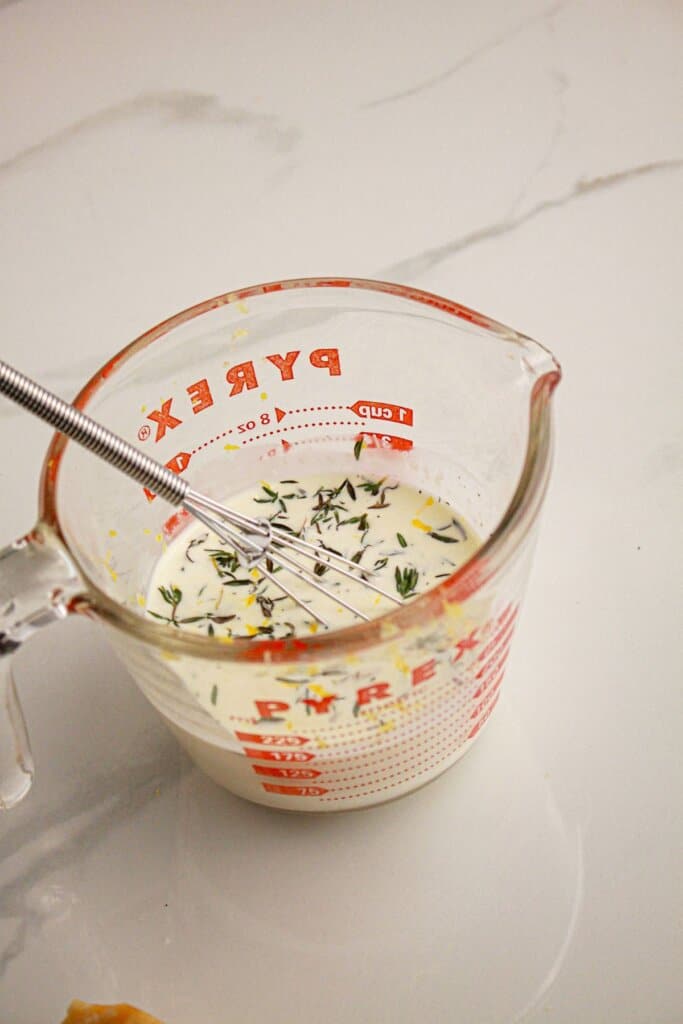 Cream sauce being mixed in a measuring cup.