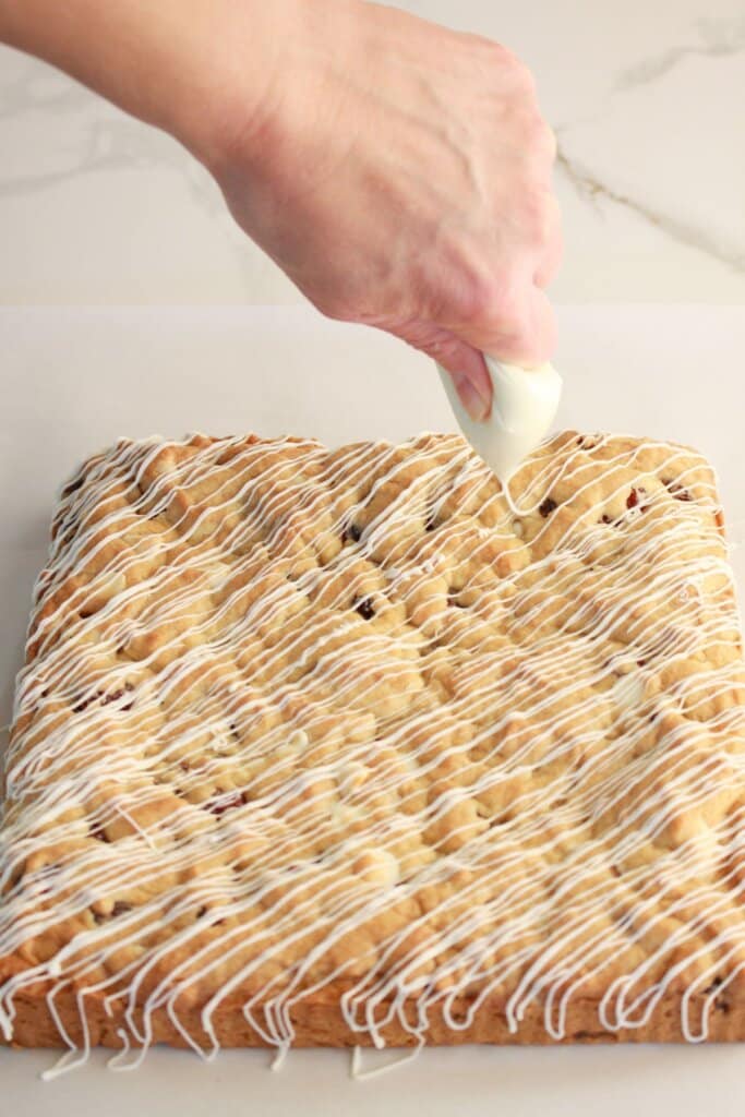 White chocolate being drizzled on bars.