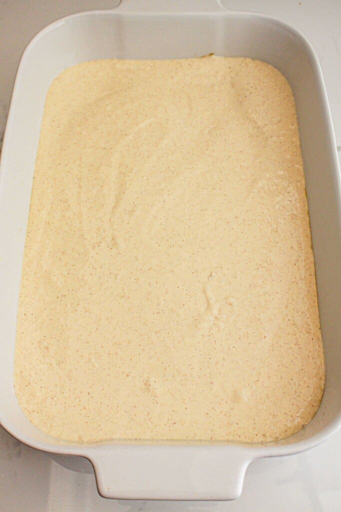 Cream cheese layer being spread in baking dish.