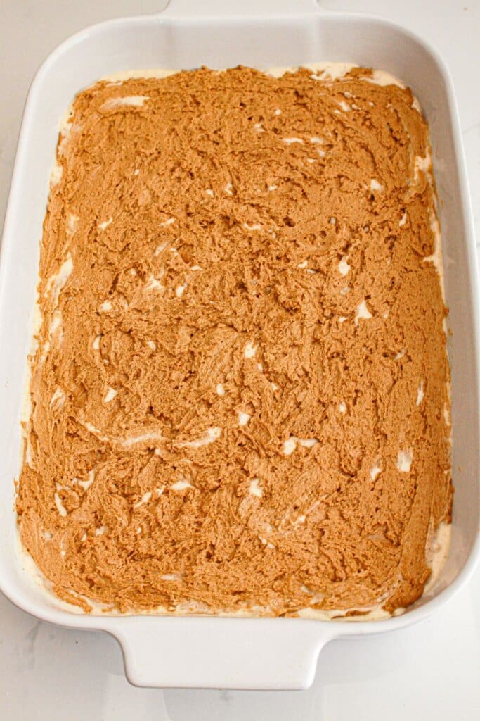 Dough being spread on top of cream cheese layer.