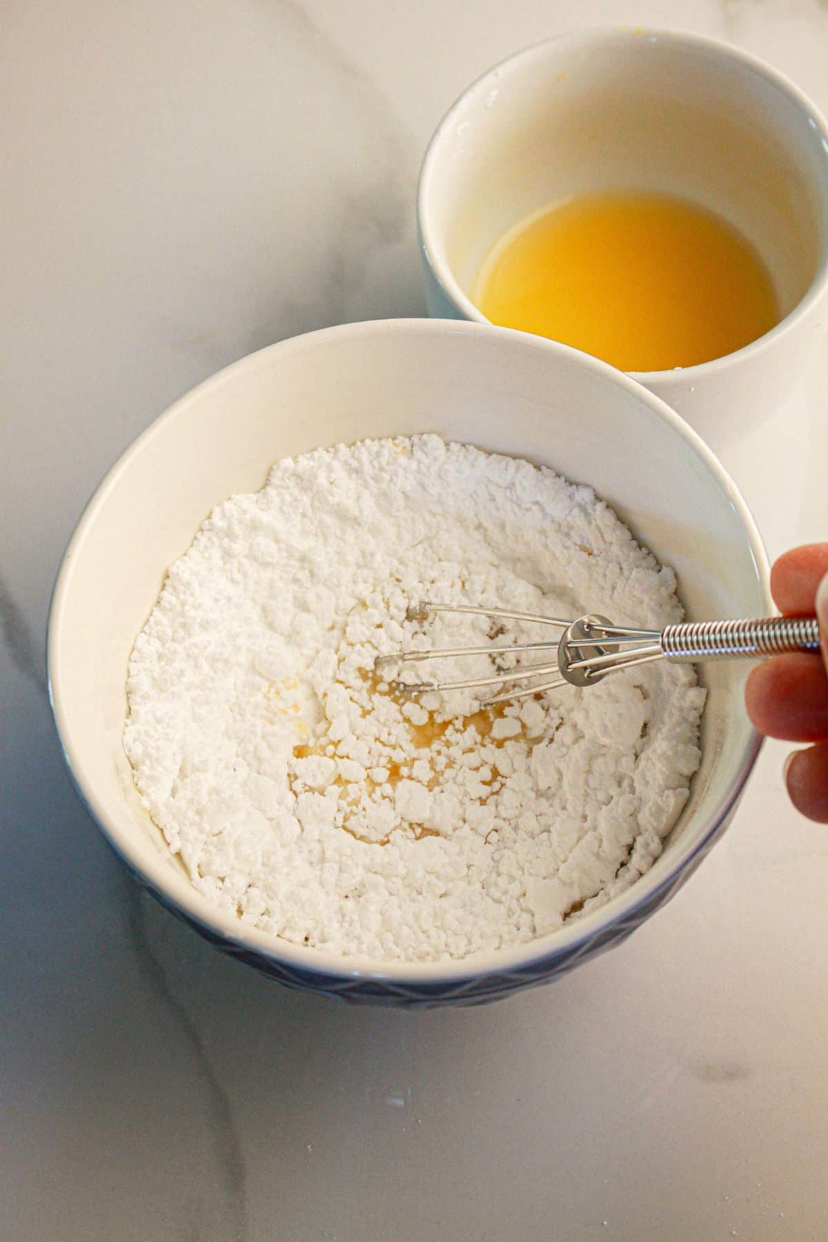 Powdered sugar and orange juice being mixed.
