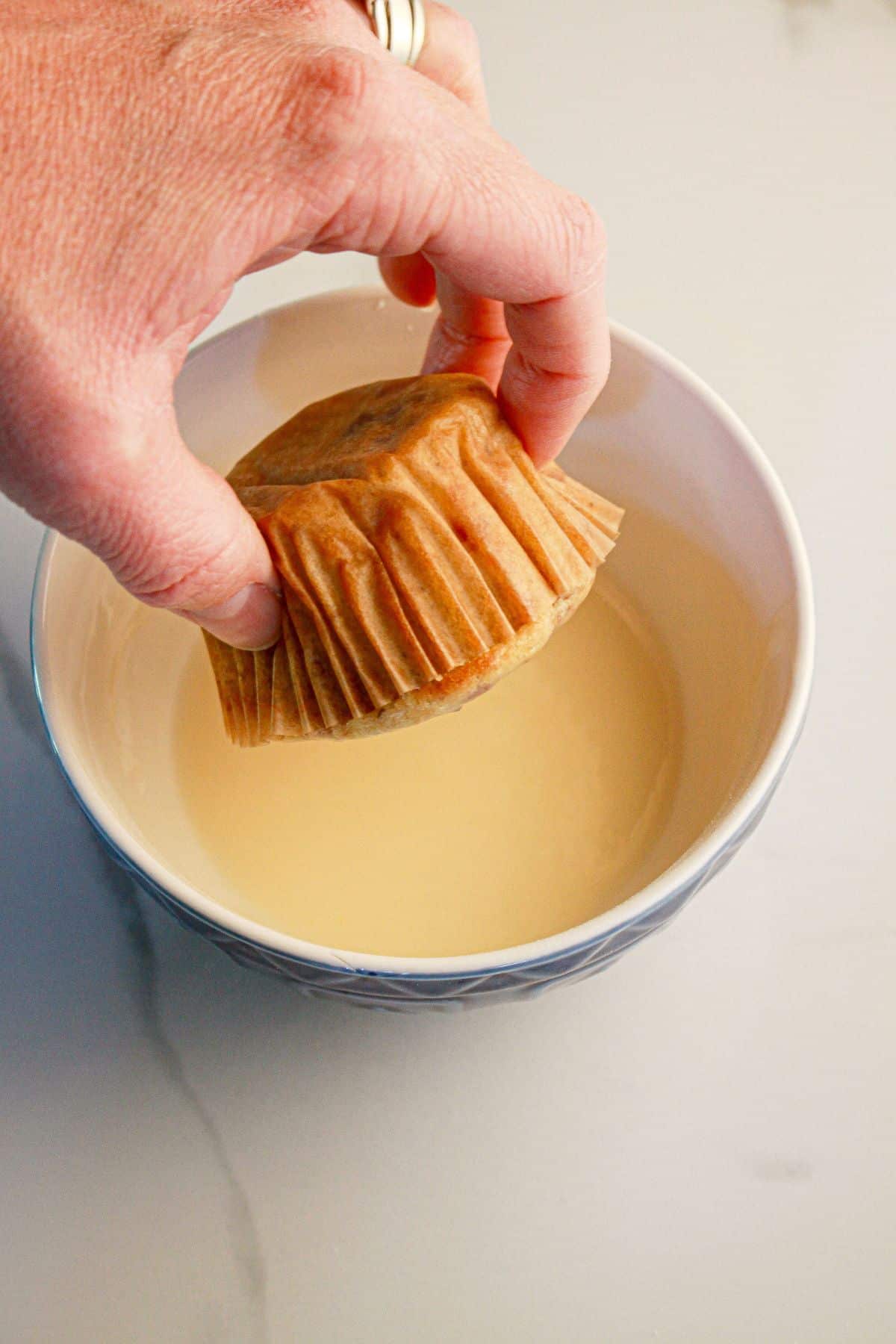Muffin being dipped in glaze.